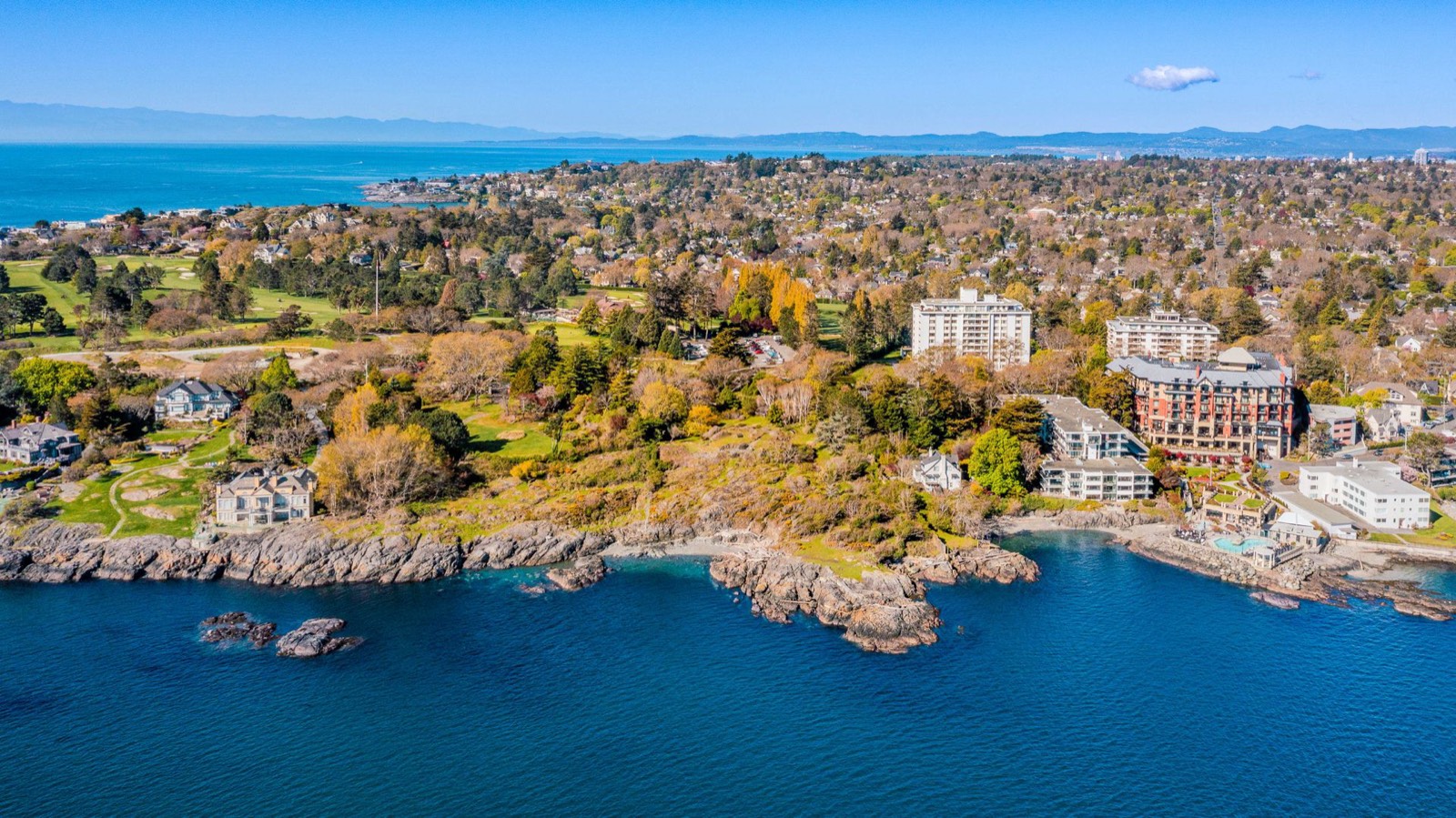 Aerial view from the water looking north across the site toward the Victoria Golf Club, with an eleven-storey apartment building and the Oak Bay Beach Hotel to the east
